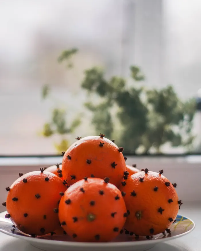 Pomarańcze nabite goździkami na talerzu przy oknie